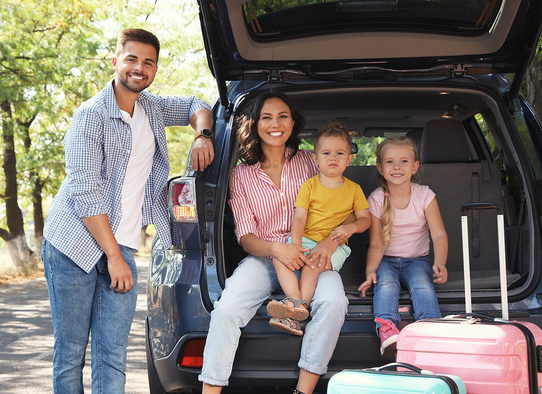 About Our Agency - Happy Family Sitting in the Back of Their Car as They Prepare for a Road Trip